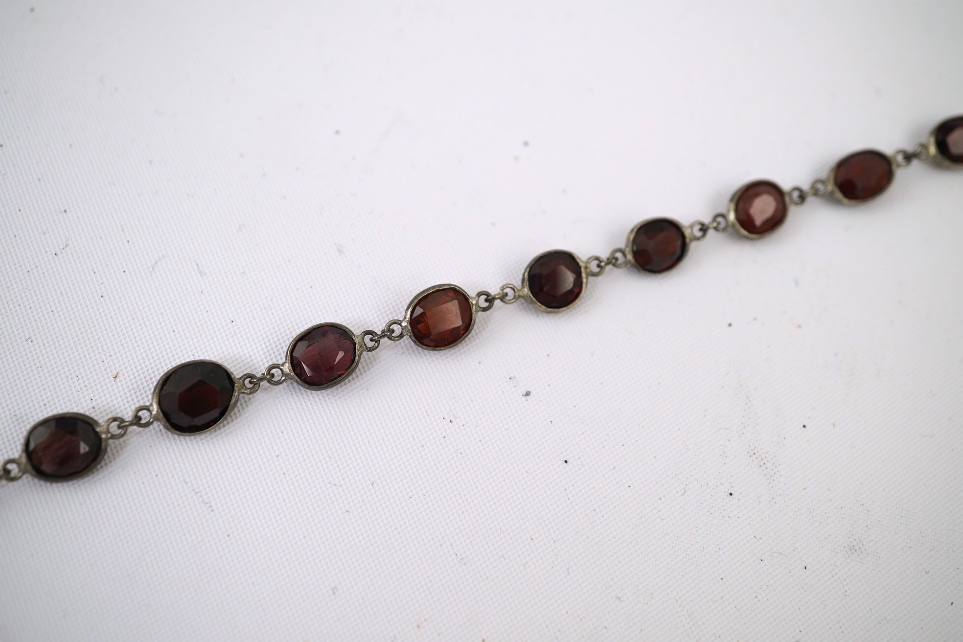 A Victorian silver and graduated oval cut two colour garnet set drop spectacle necklace, 74cm. Condition - poor to fair